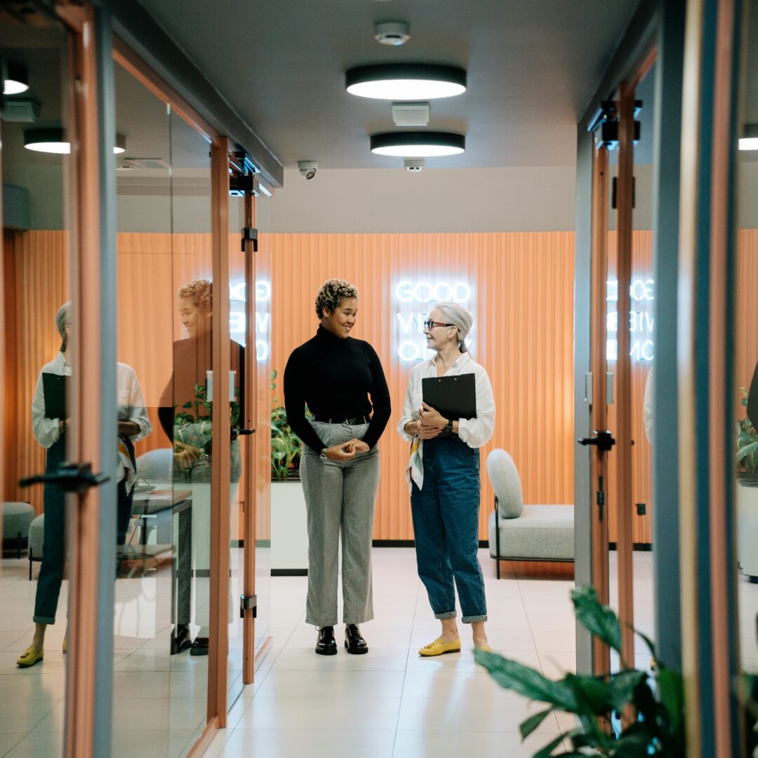 Two colleagues walking and having a discussion in an office hallway.