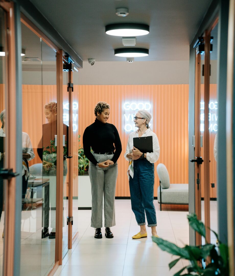 Two colleagues walking and having a discussion in an office hallway.